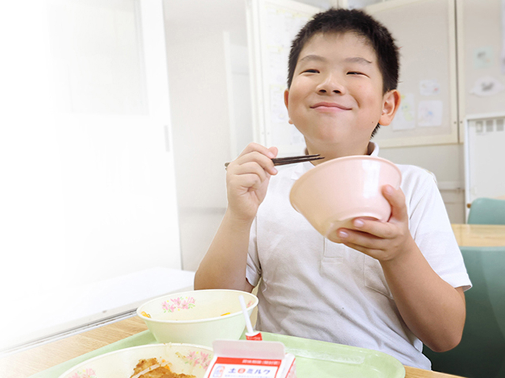 小学生が地場産野菜を使った学校給食を食べる様子