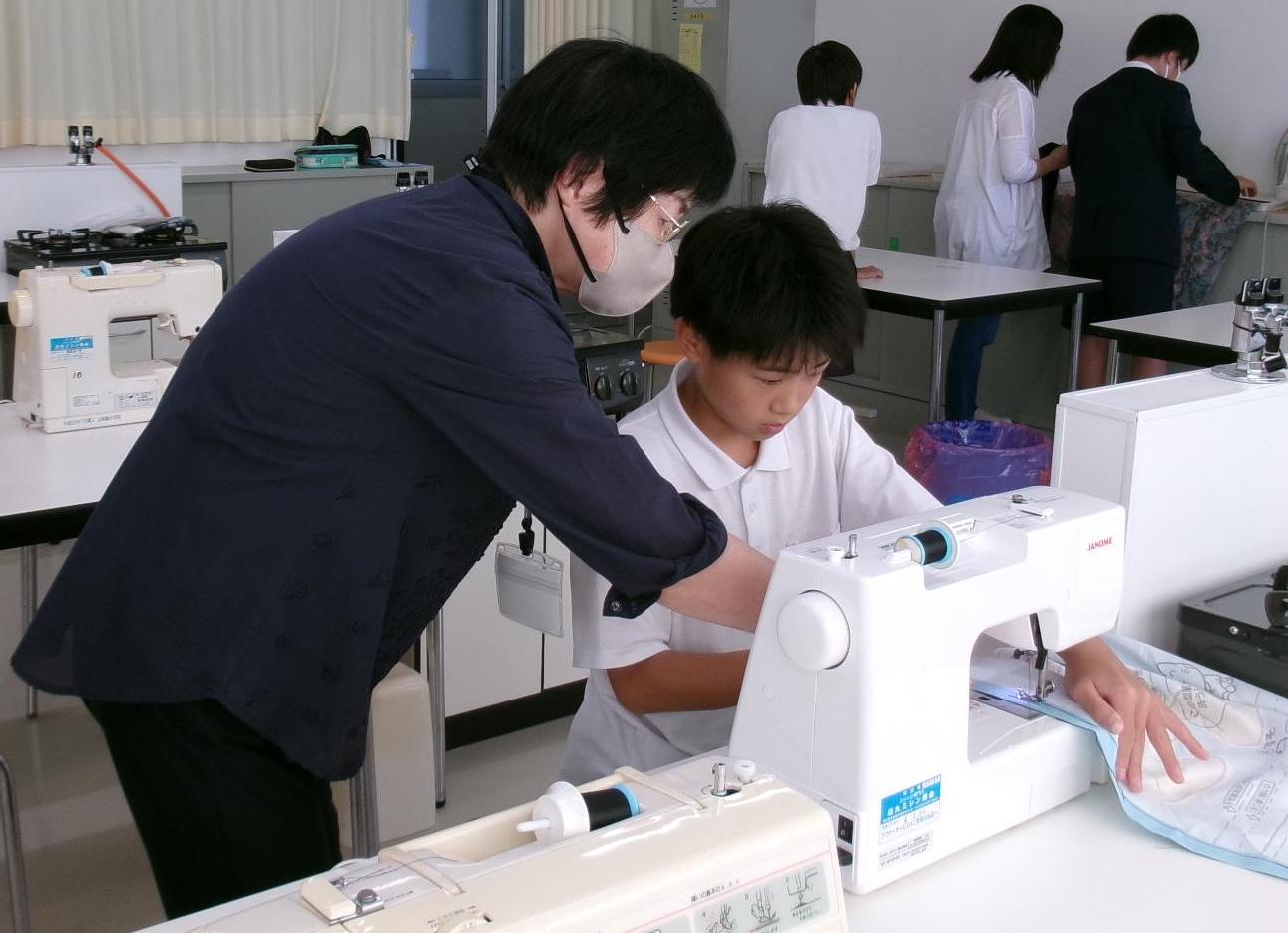 家庭科の授業で地域住民がミシンの操作を サポート。一人一人のペースに合わせて指導
