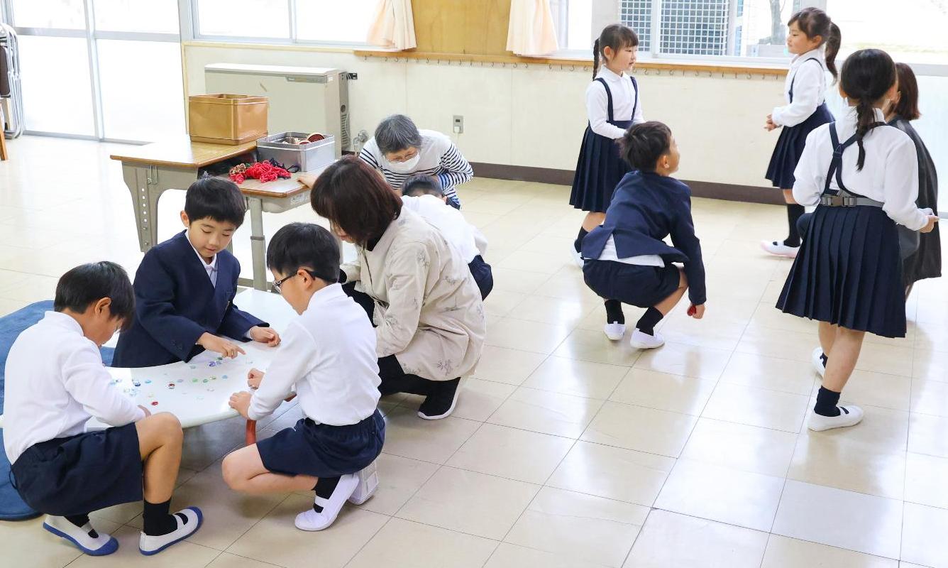地域ボランティアが見守る中、昔遊び の玩具や絵本がある部屋で思い思いに 過ごす児童