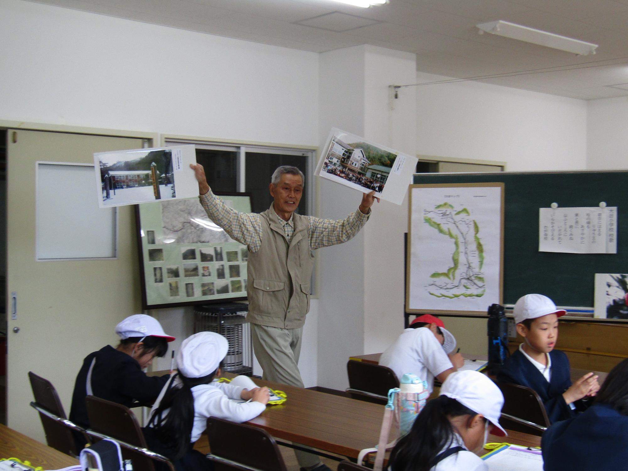 様々な写真を手に持ち説明する地域住民