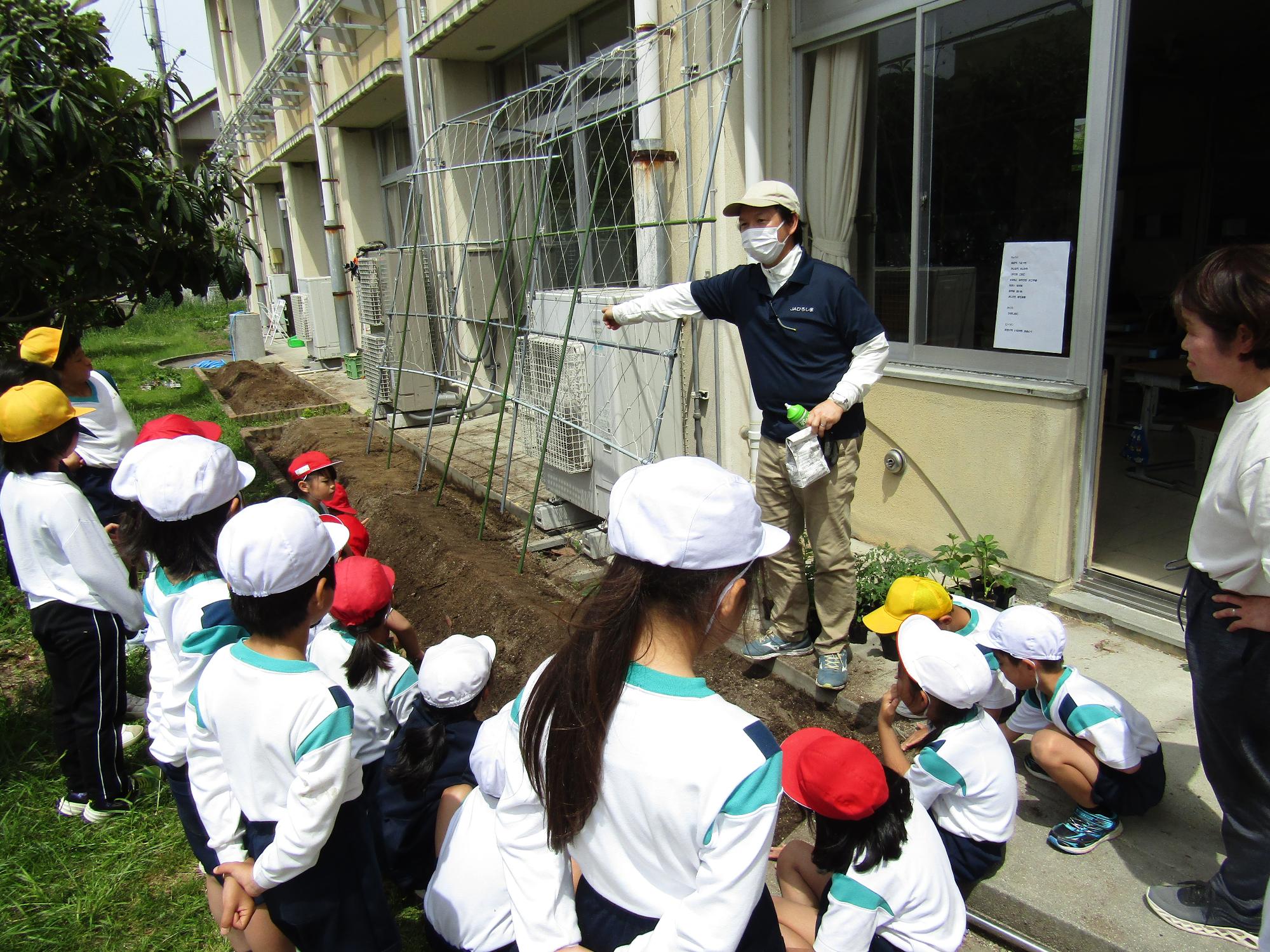 学級園を囲んでJAスタッフの話を聞く子供達