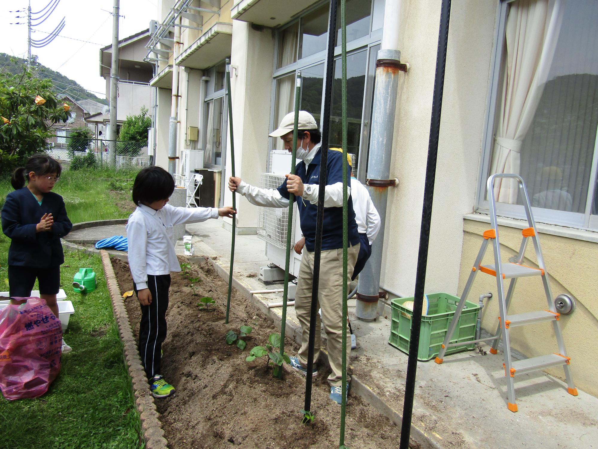 たくさんの支柱を指していくJA職員と男子児童