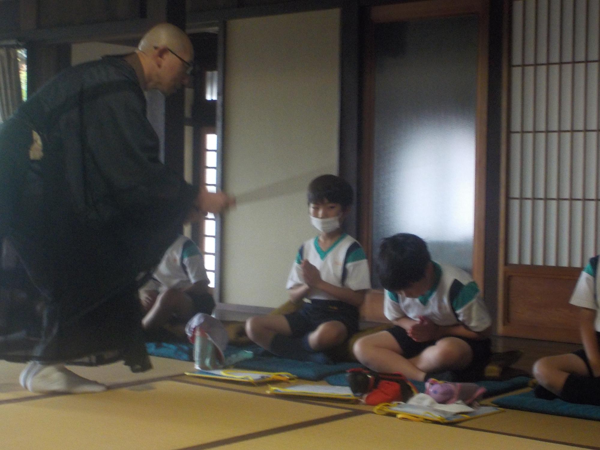 和尚から警策でたたかれる男子児童