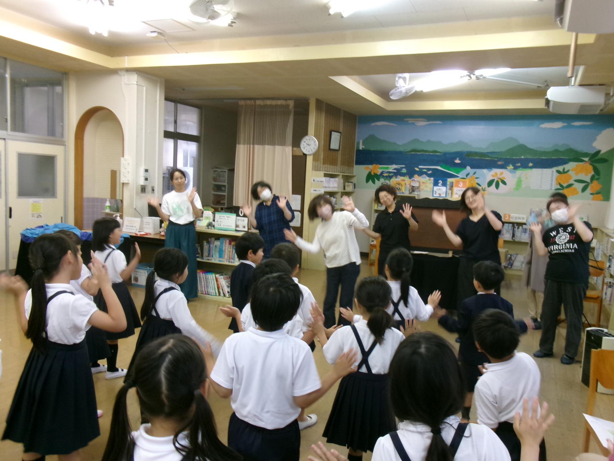 読み聞かせボランティアたちの真似をして手遊びをする様子