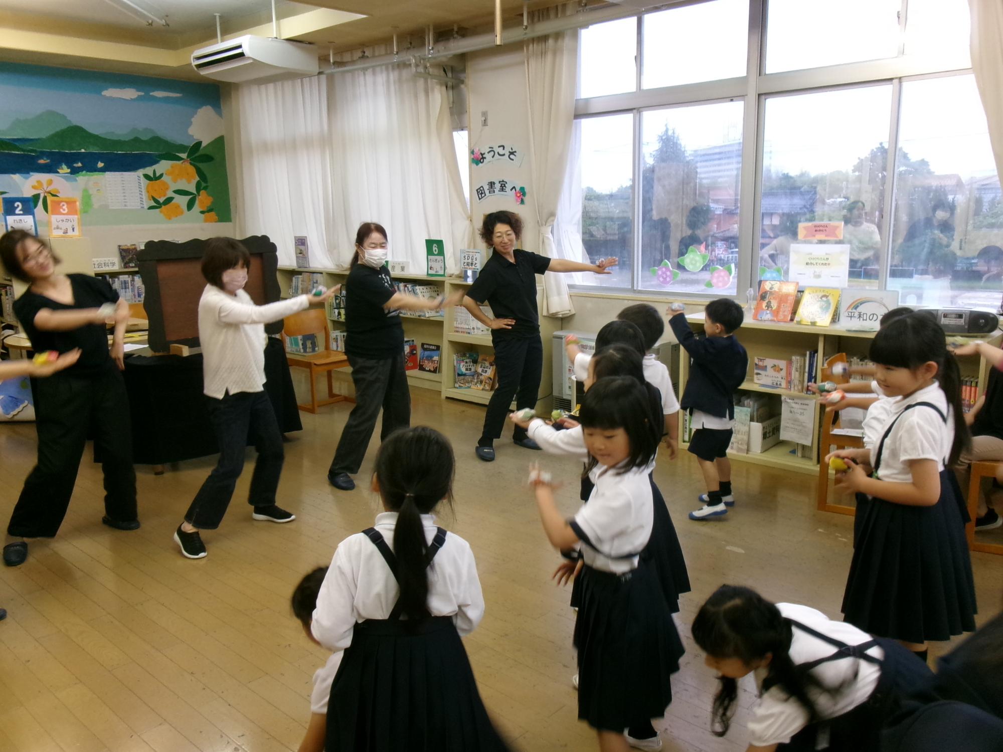 手の甲にお手玉をのせて踊る子供達とボランティアさんたち