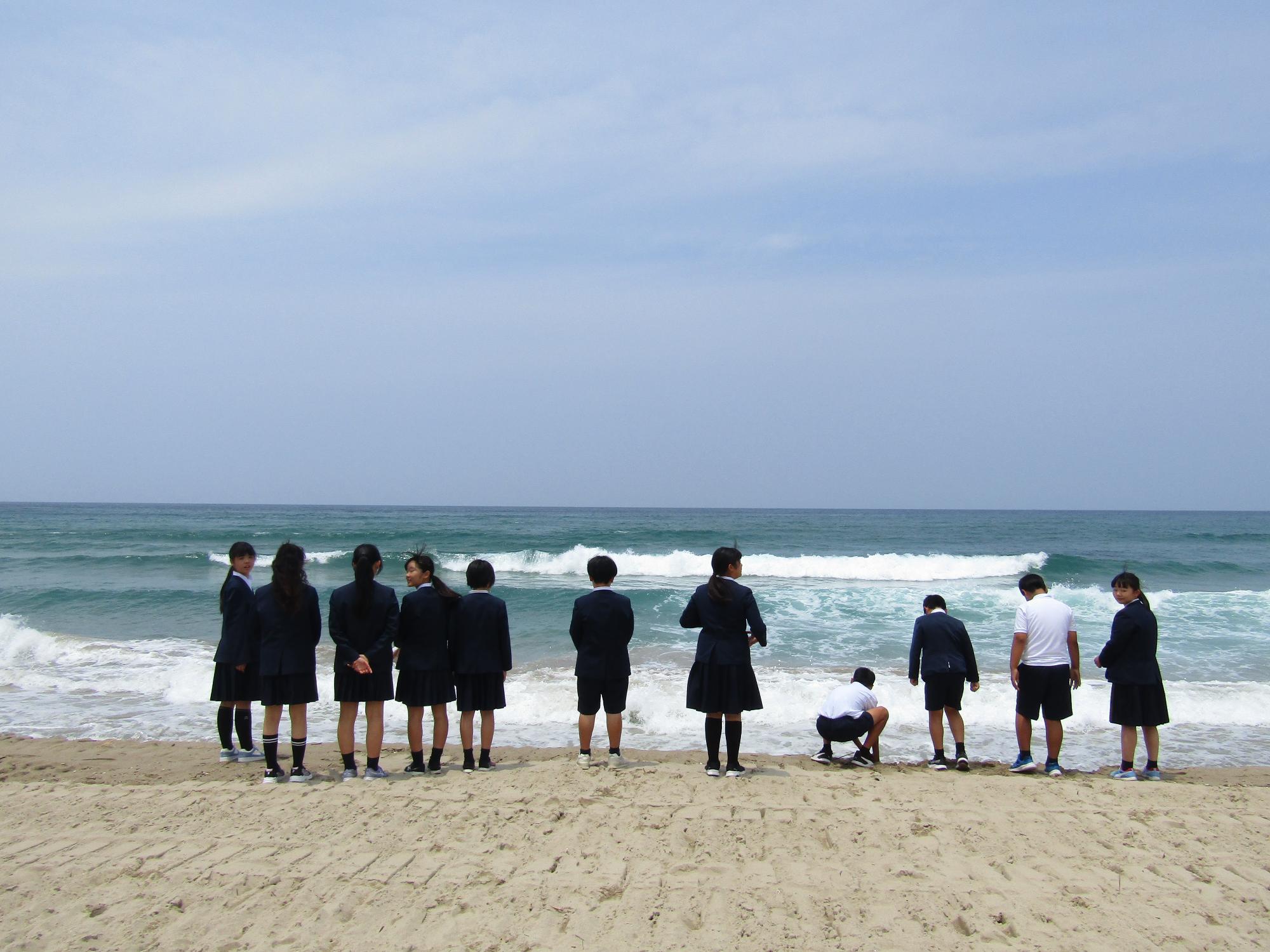 小休憩で海辺に立ち寄り、海を見ている子供たちの背中