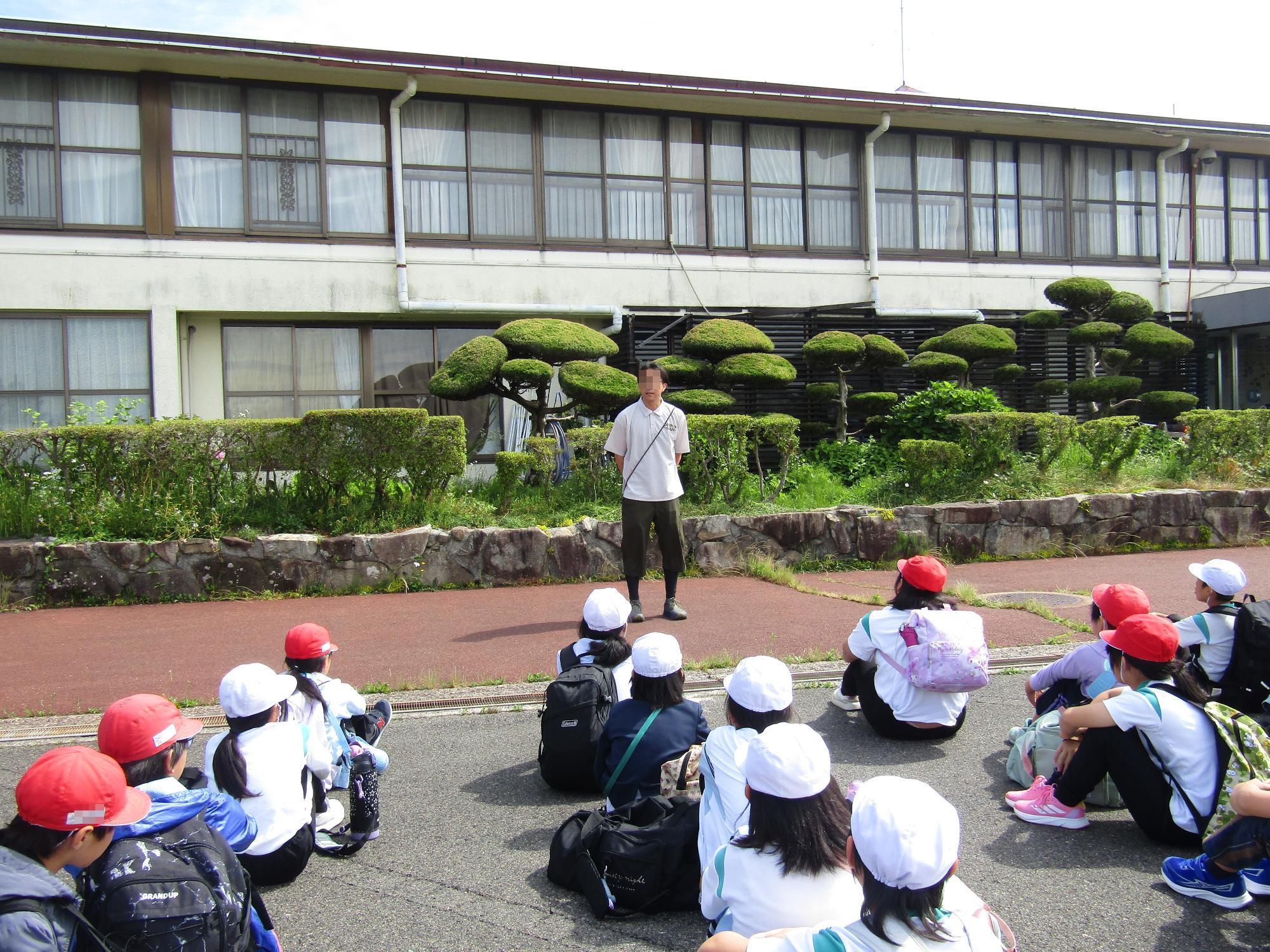 野呂山宿舎の前でスタッフの話を聞く子供達