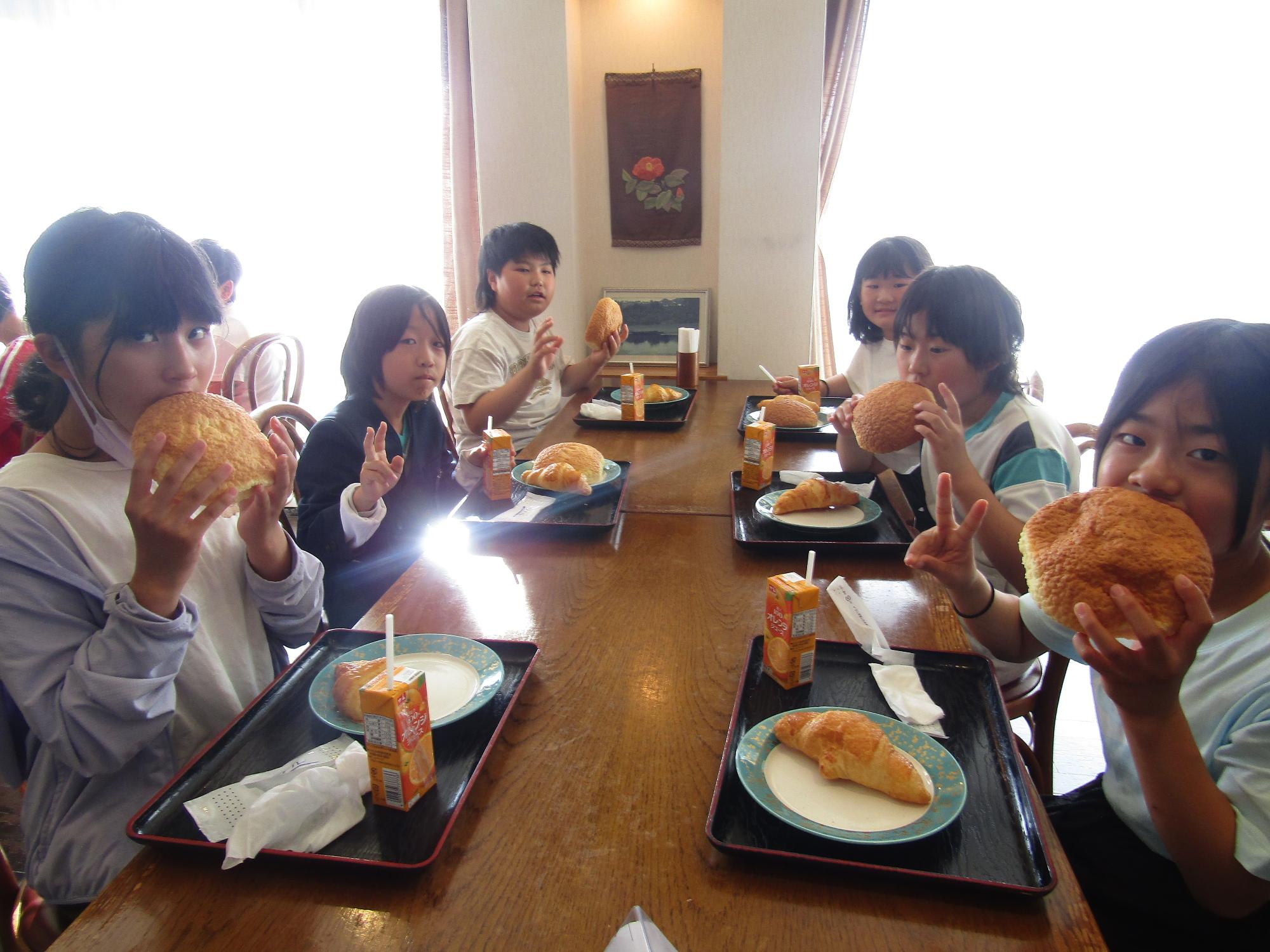 朝食の大きなパンをほおばる子供たち