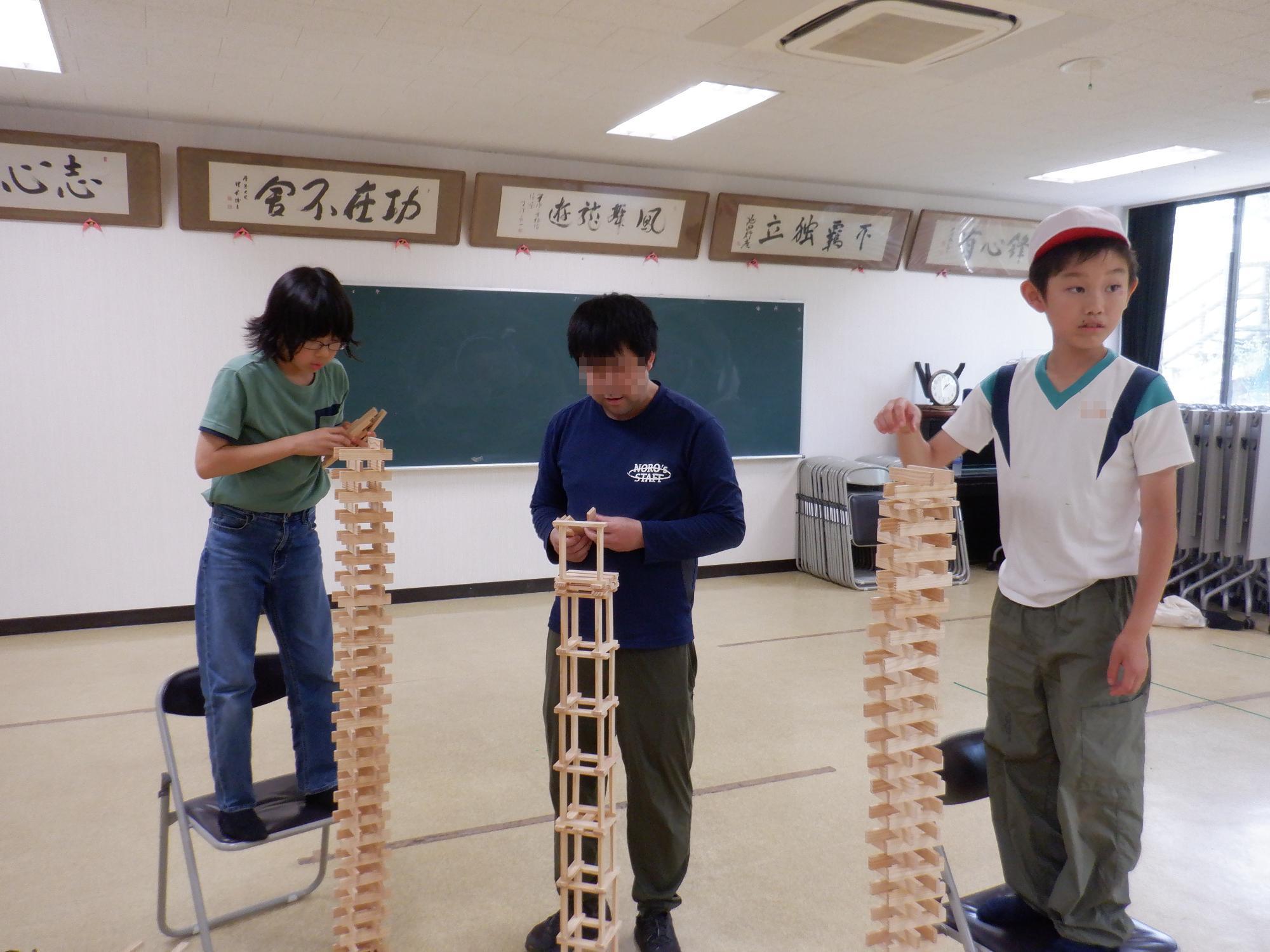 室内でカプラを積み重ねて競争する子供達とスタッフさん