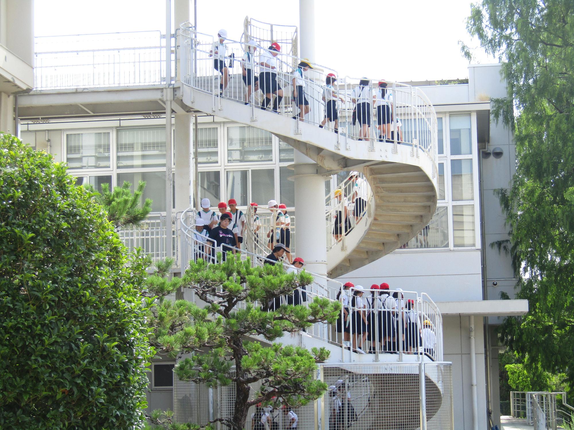 屋外螺旋階段から下へ降りる子供達