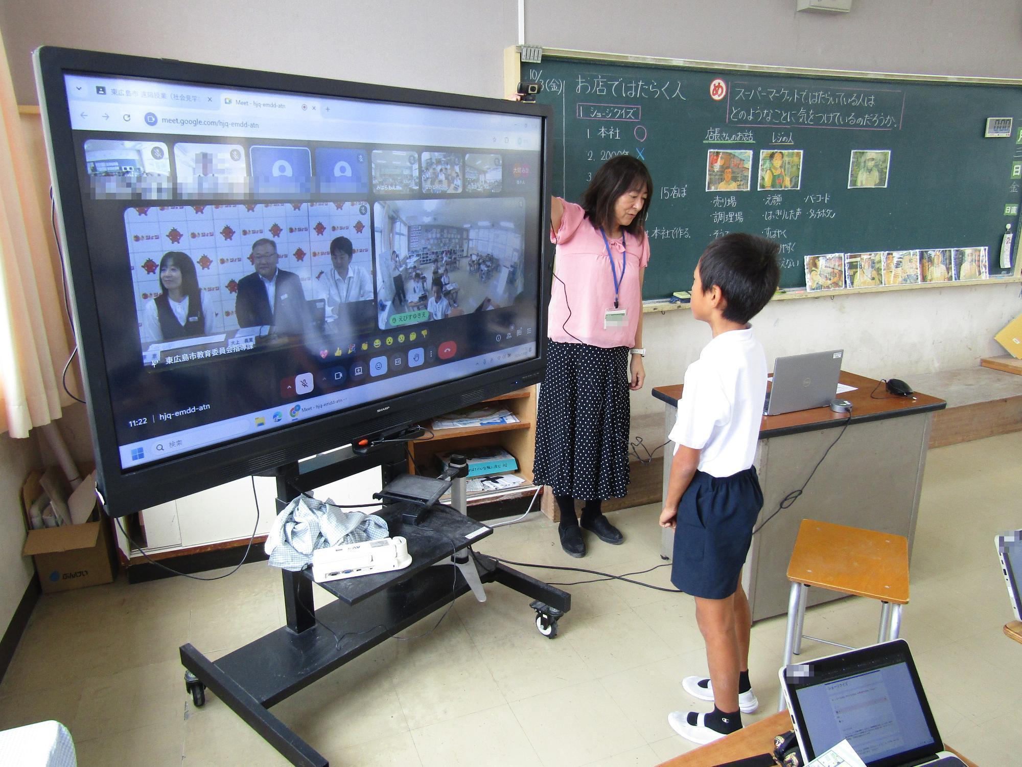電子黒板に向かって発表する男子児童