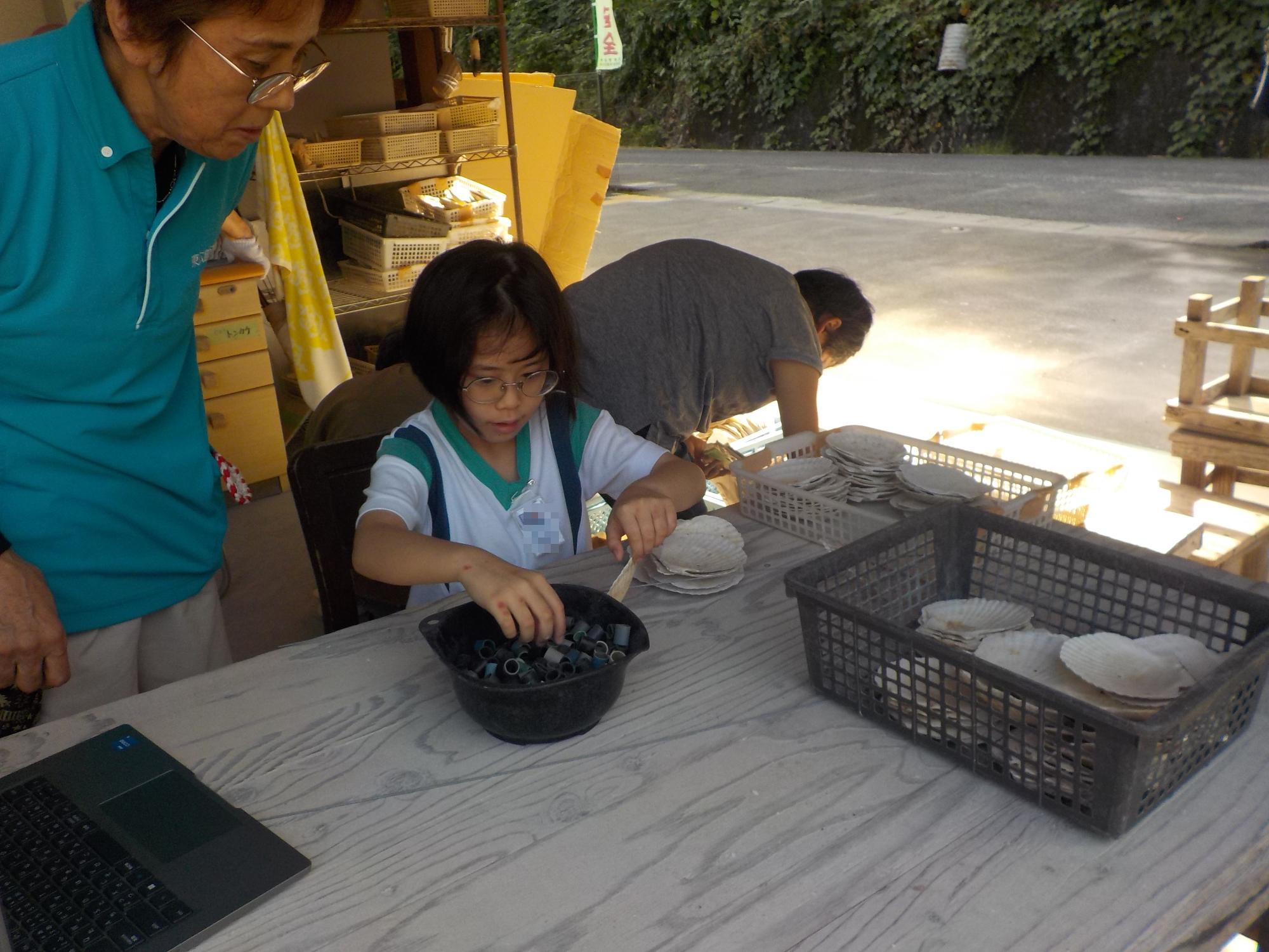 道具の仕分けをする女子児童と見守るスタッフ