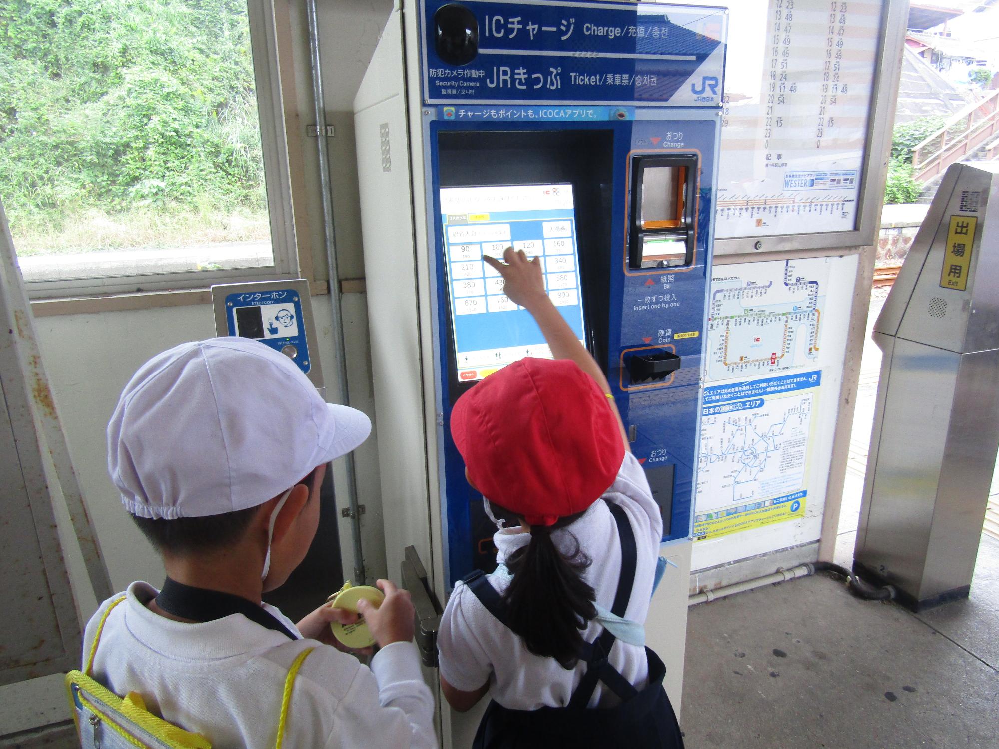 駅の券売機で切符を買う女子児童