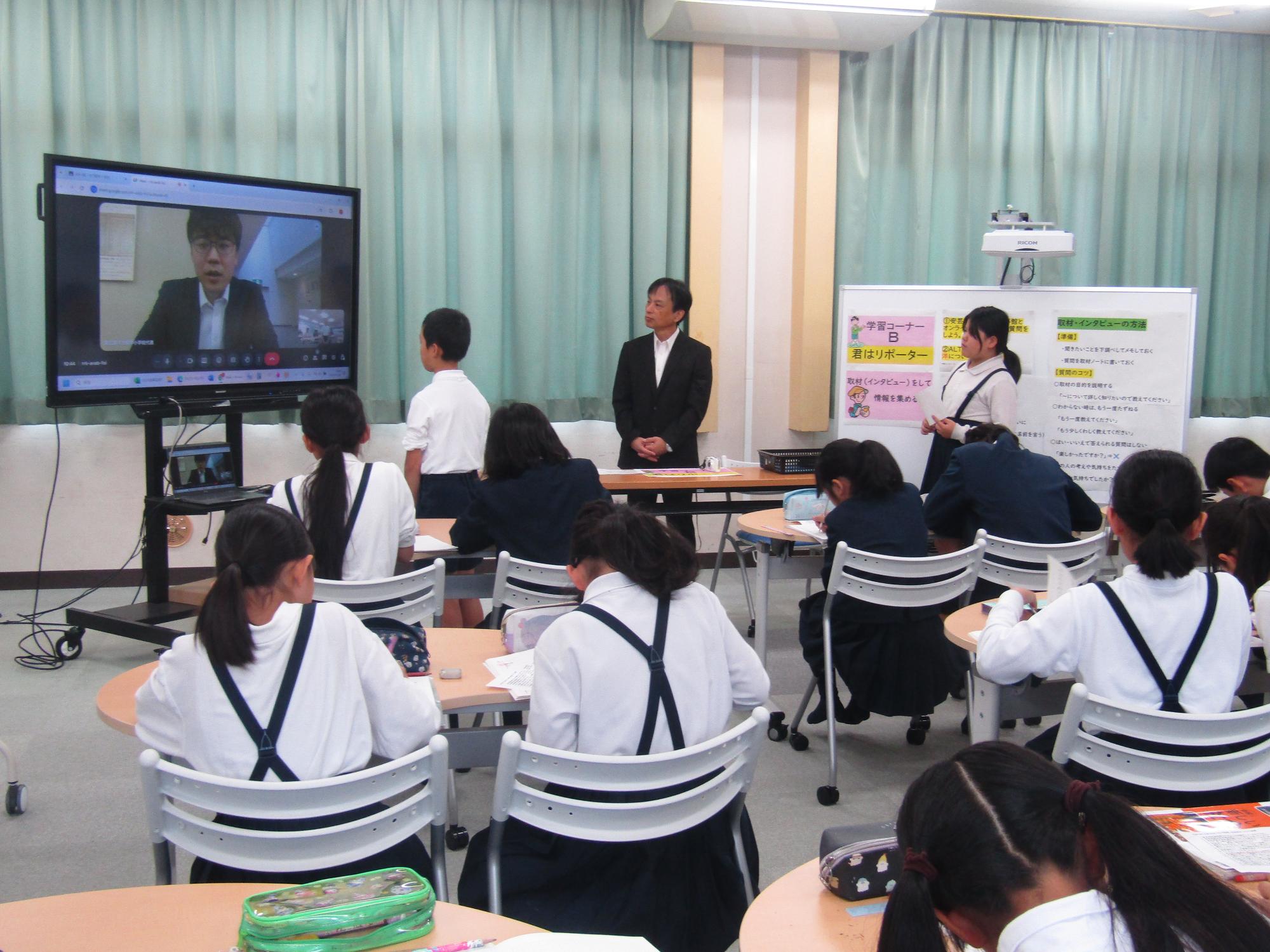 ラーニングルームで電子黒板を見ながらメモを取る子供たち