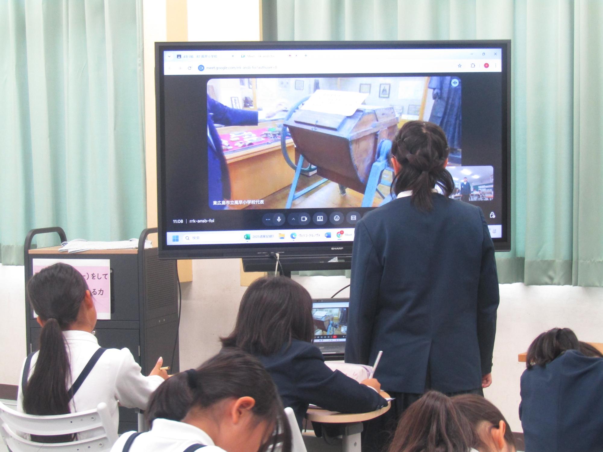 電子黒板に向かって質問する女児とメモを取る子供たち