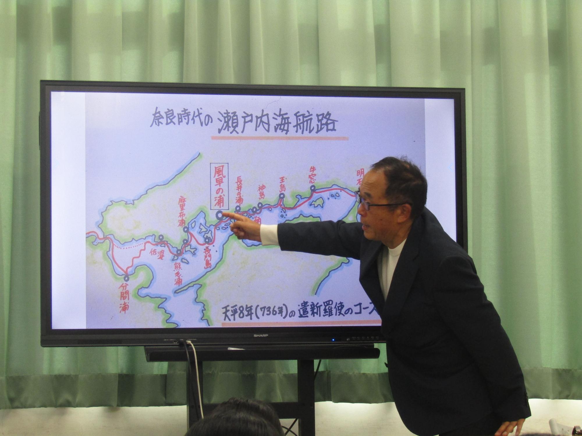 手書きの地図を指さし、説明する男性