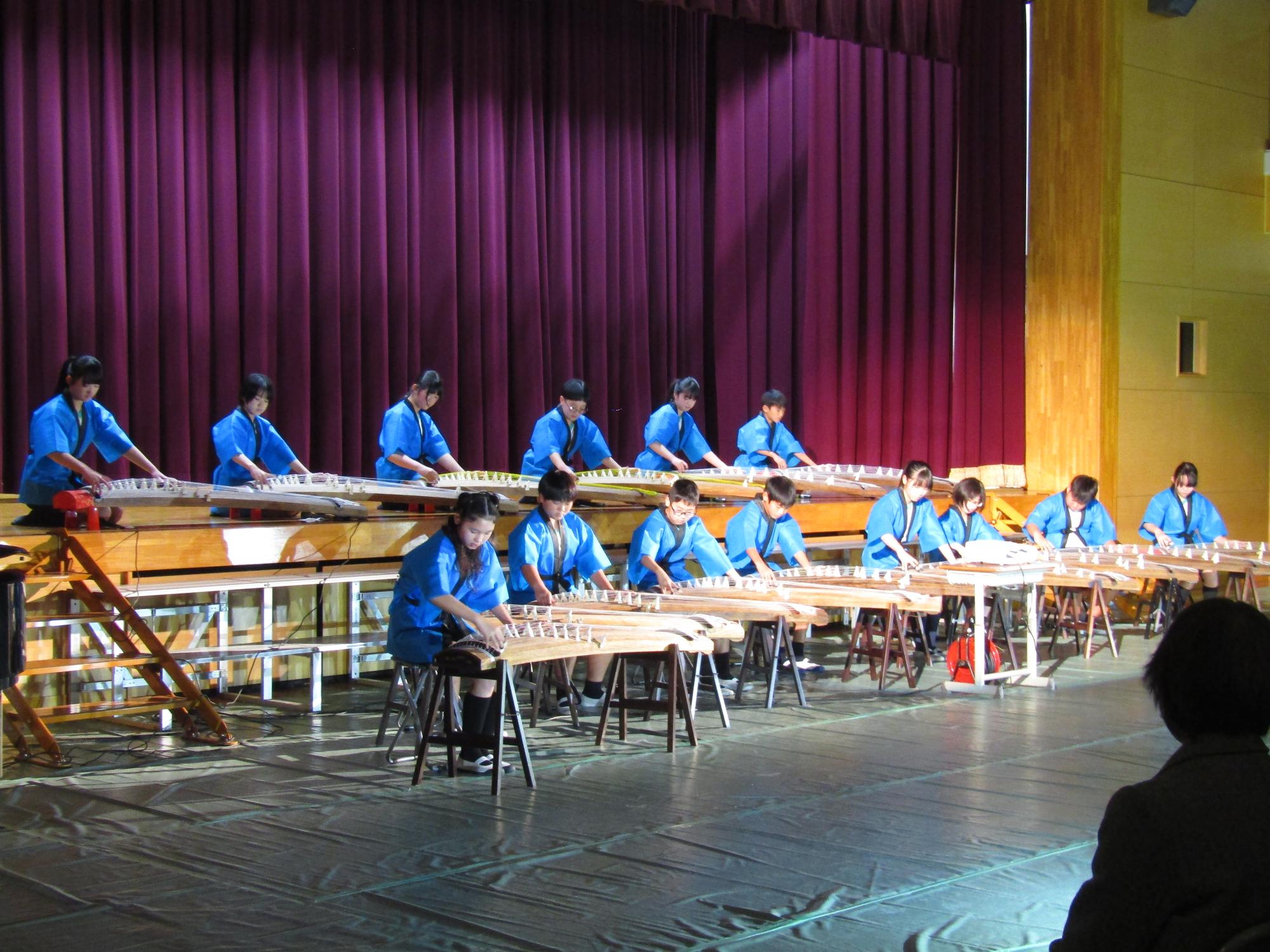 青い法被を着て箏の演奏をする6年生たち