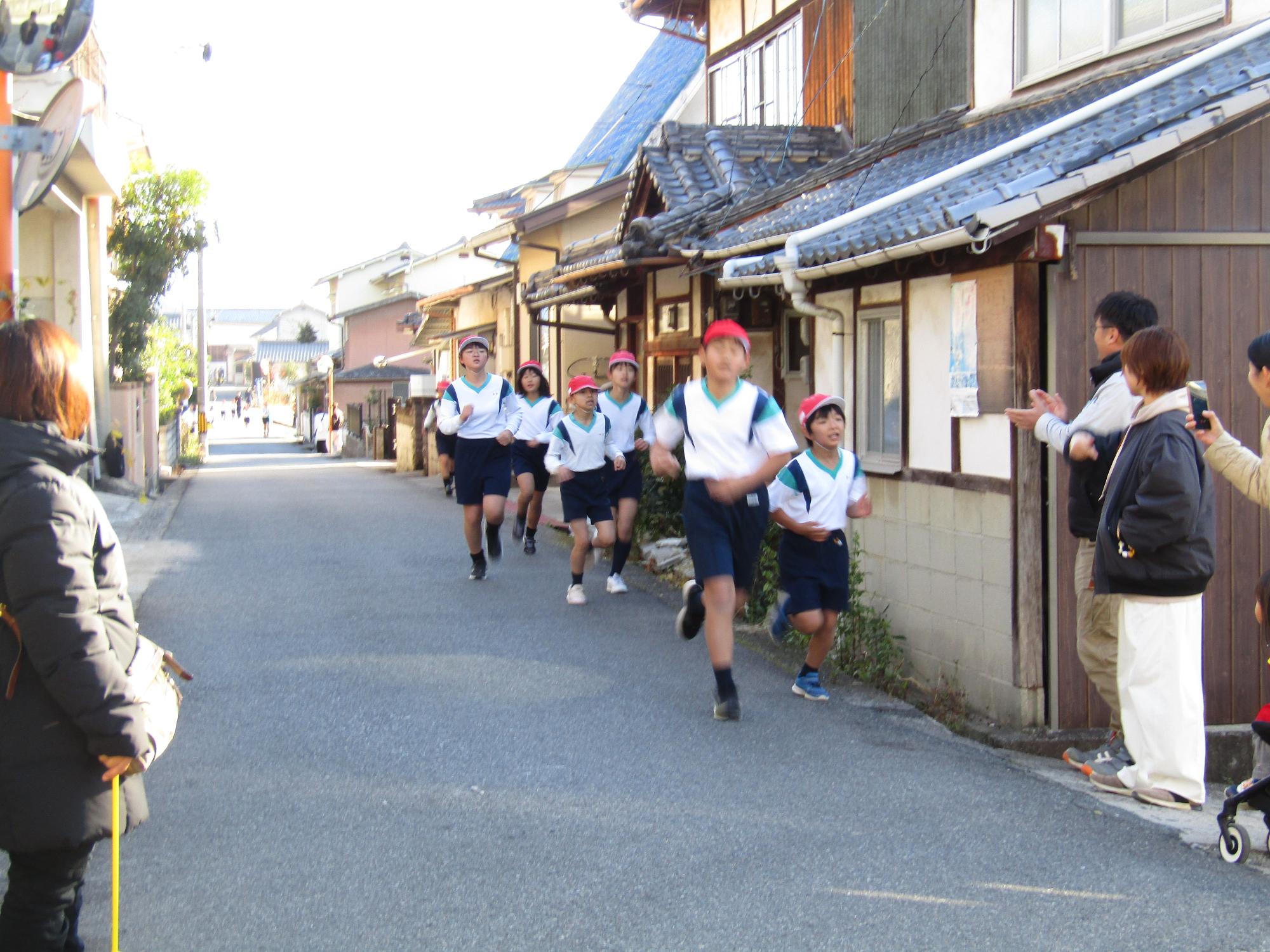 沿道を恥じる4年生の集団と応援する保護者達