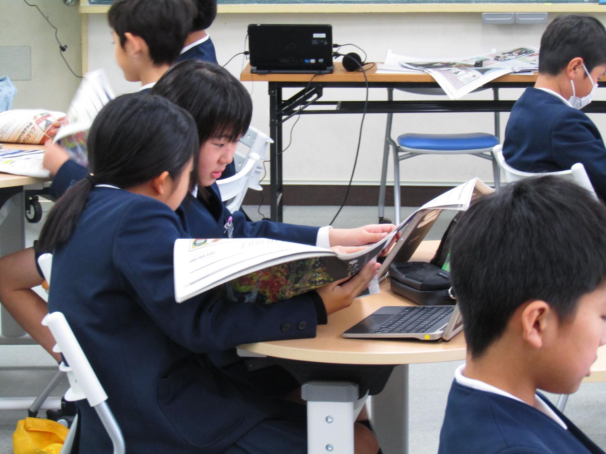 見本のフリーペーパーを見ている女子児童たち