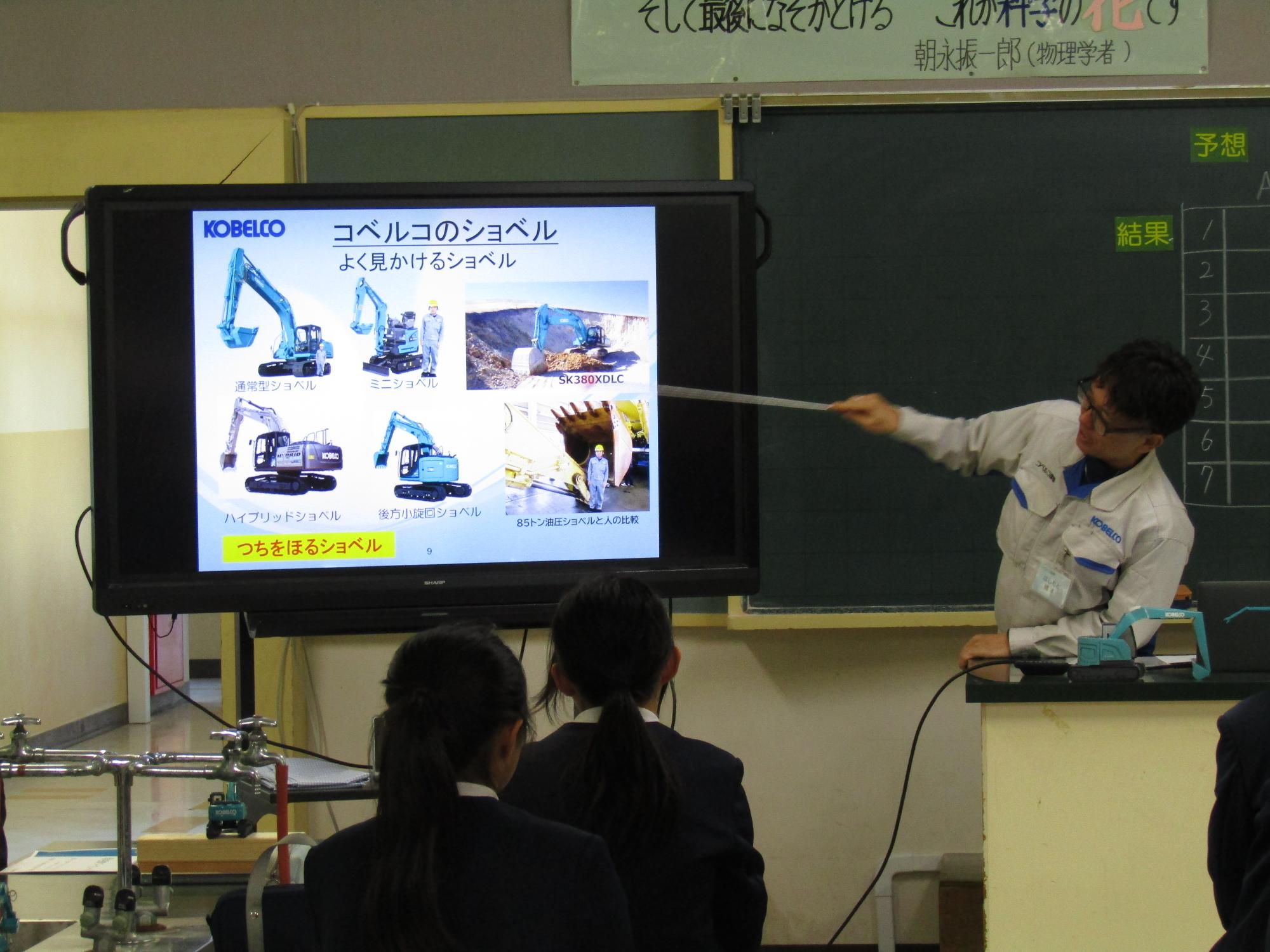教壇で電子黒板をつかって説明するコベルコ建機職員