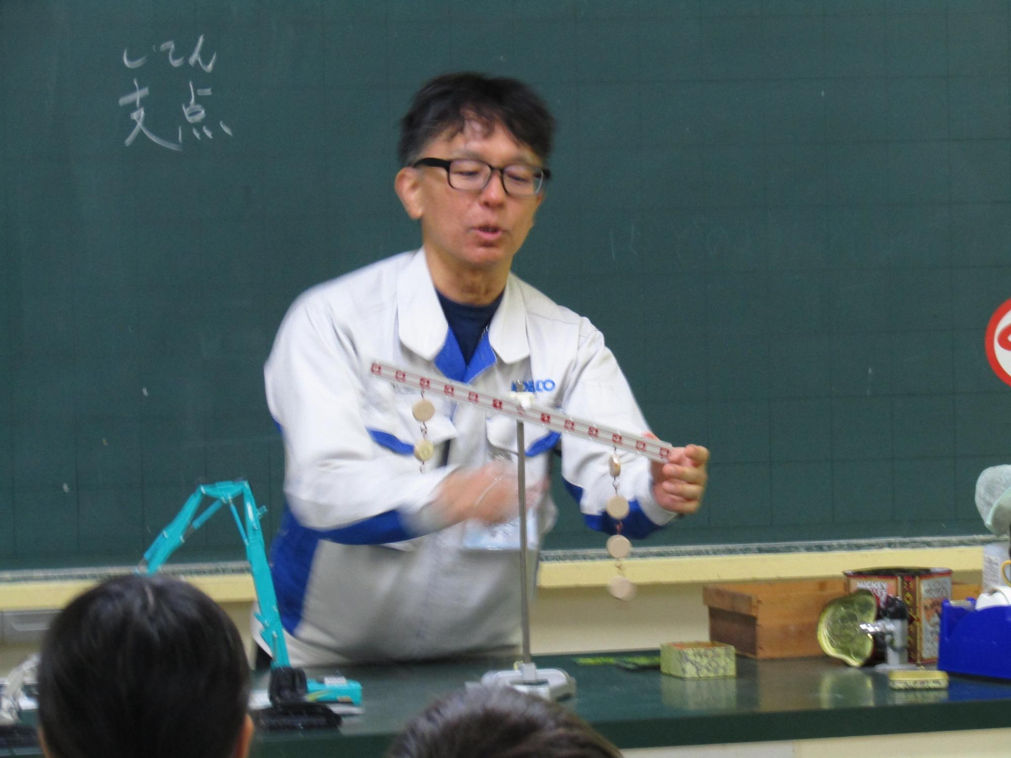 てんびんを使って説明する職員