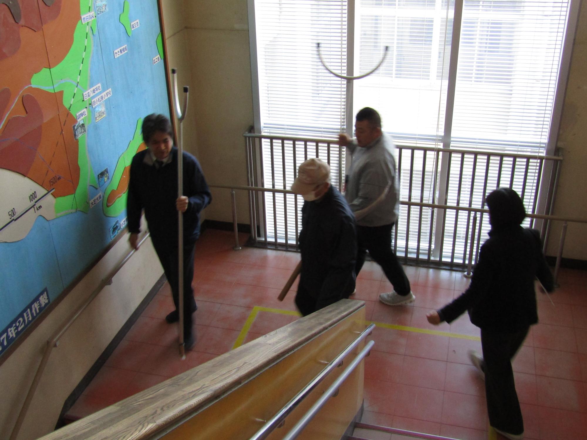 階段の踊り場で不審者役の男性を囲む教職員たち