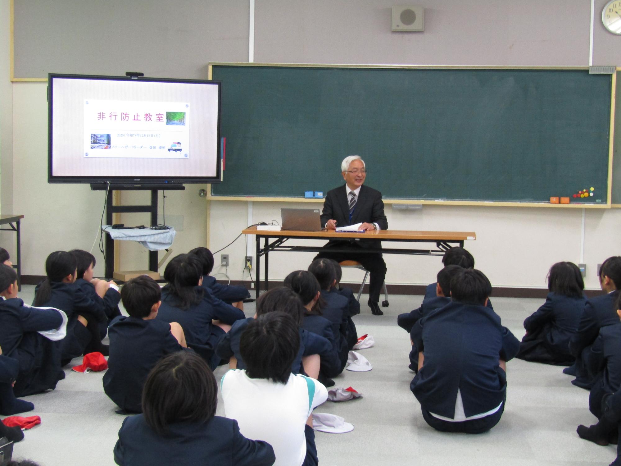 スクールガードリーダーの話を座って聞く子供たち