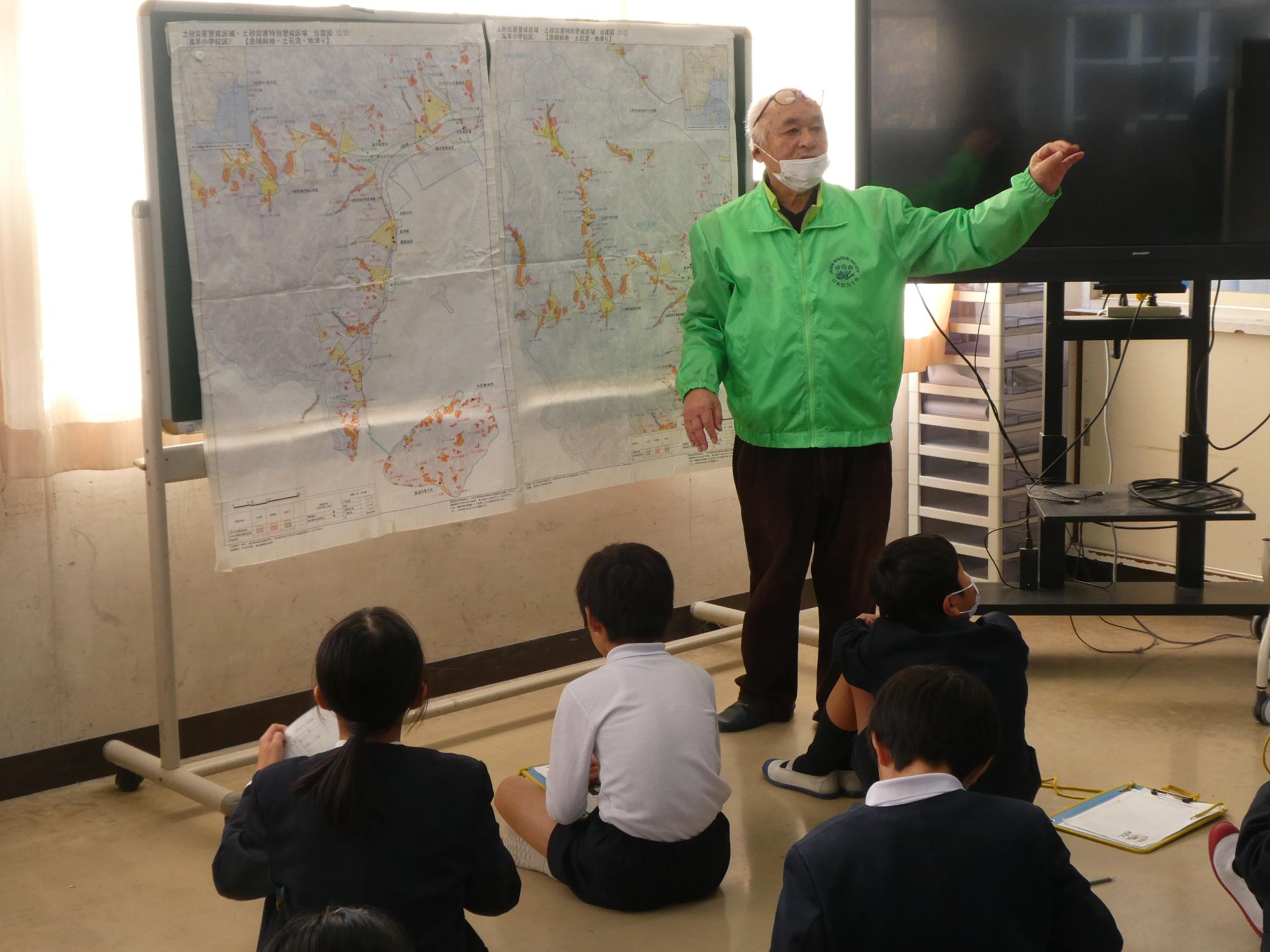 町内のハザードマップの前で話をする防災士