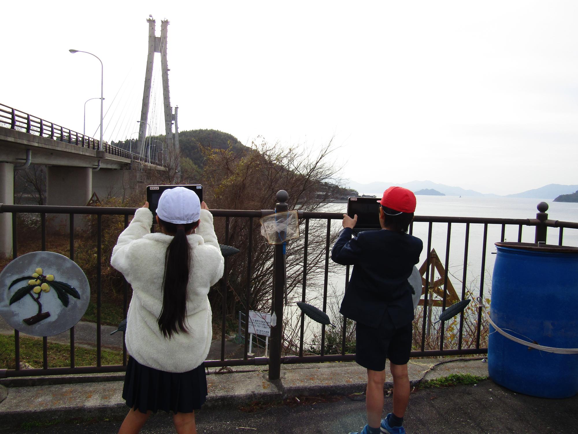 駐車場から大芝大橋を撮影する児童たち