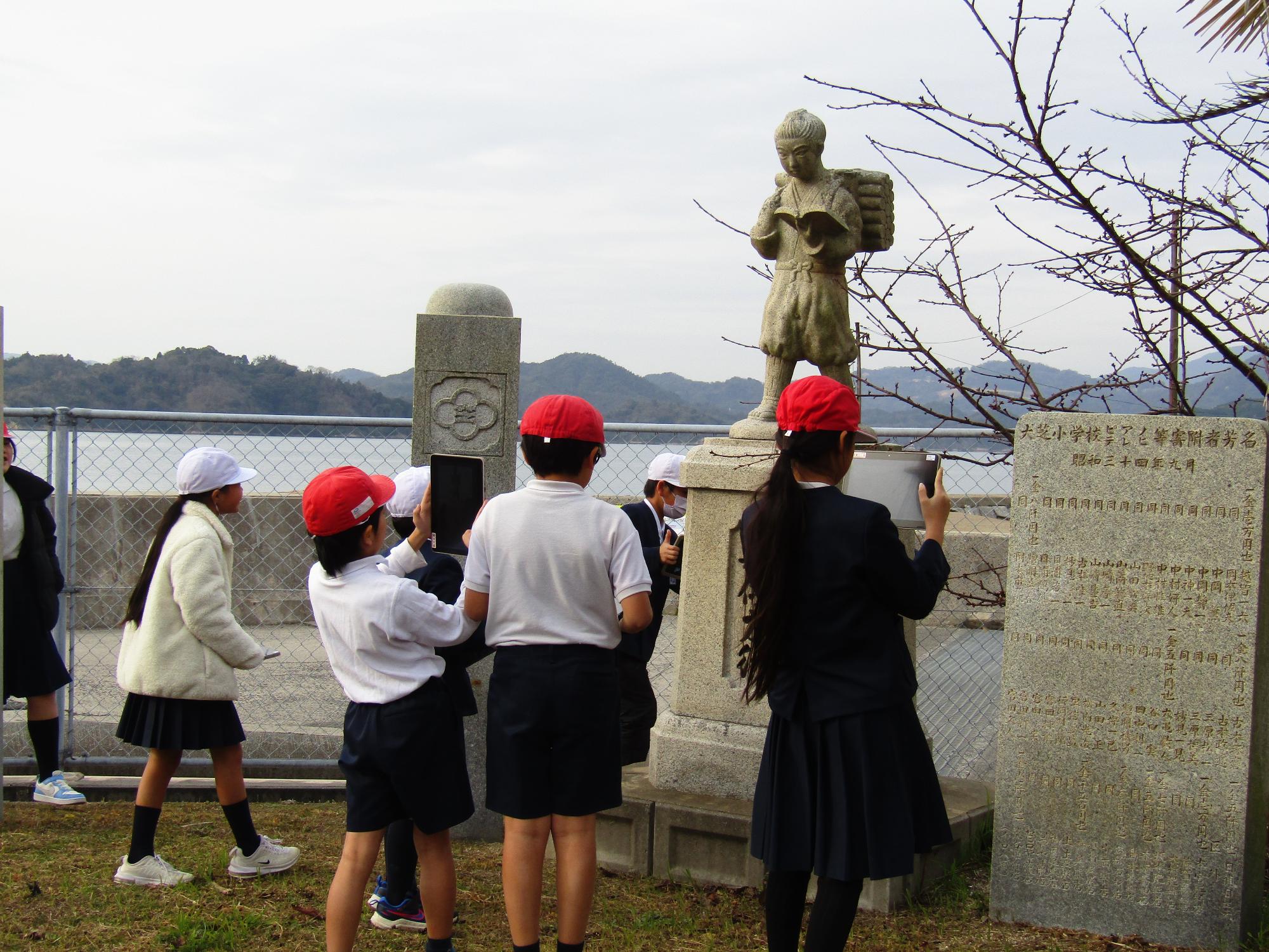 二宮金次郎像の前で撮影を始める児童たち