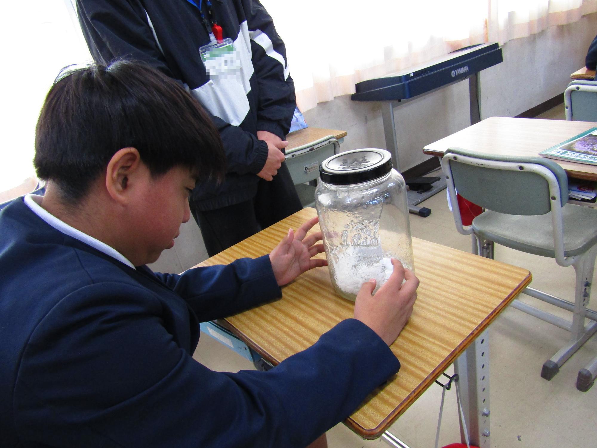 薬物の影響で溶けた脳の模型をみて驚く児童