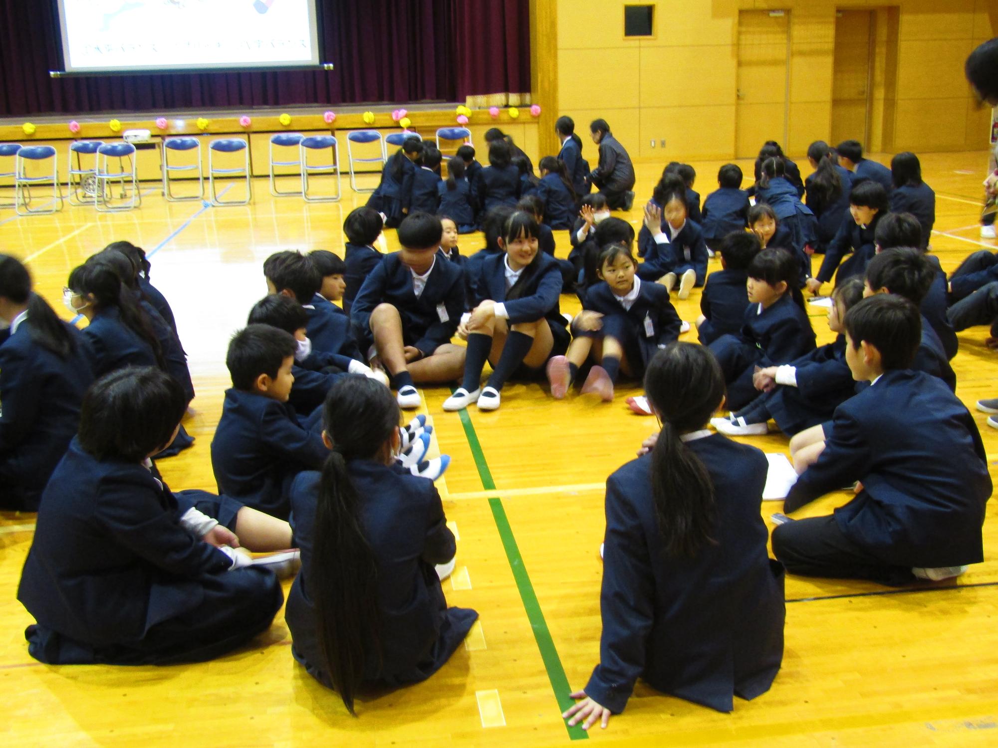 体育館フロアで円になって座る子供たち