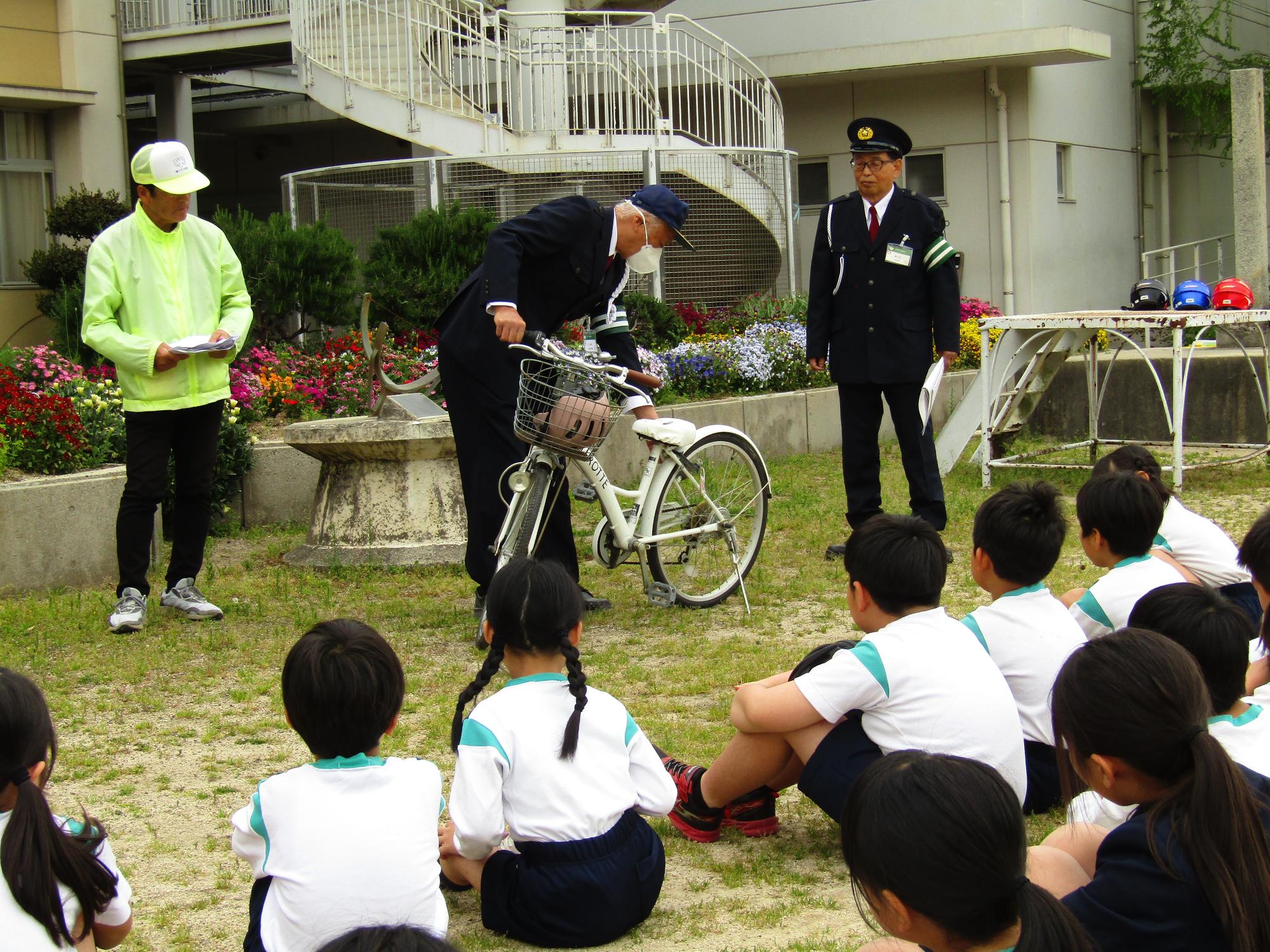 交通指導員が自転車点検をする様子を見ている児童