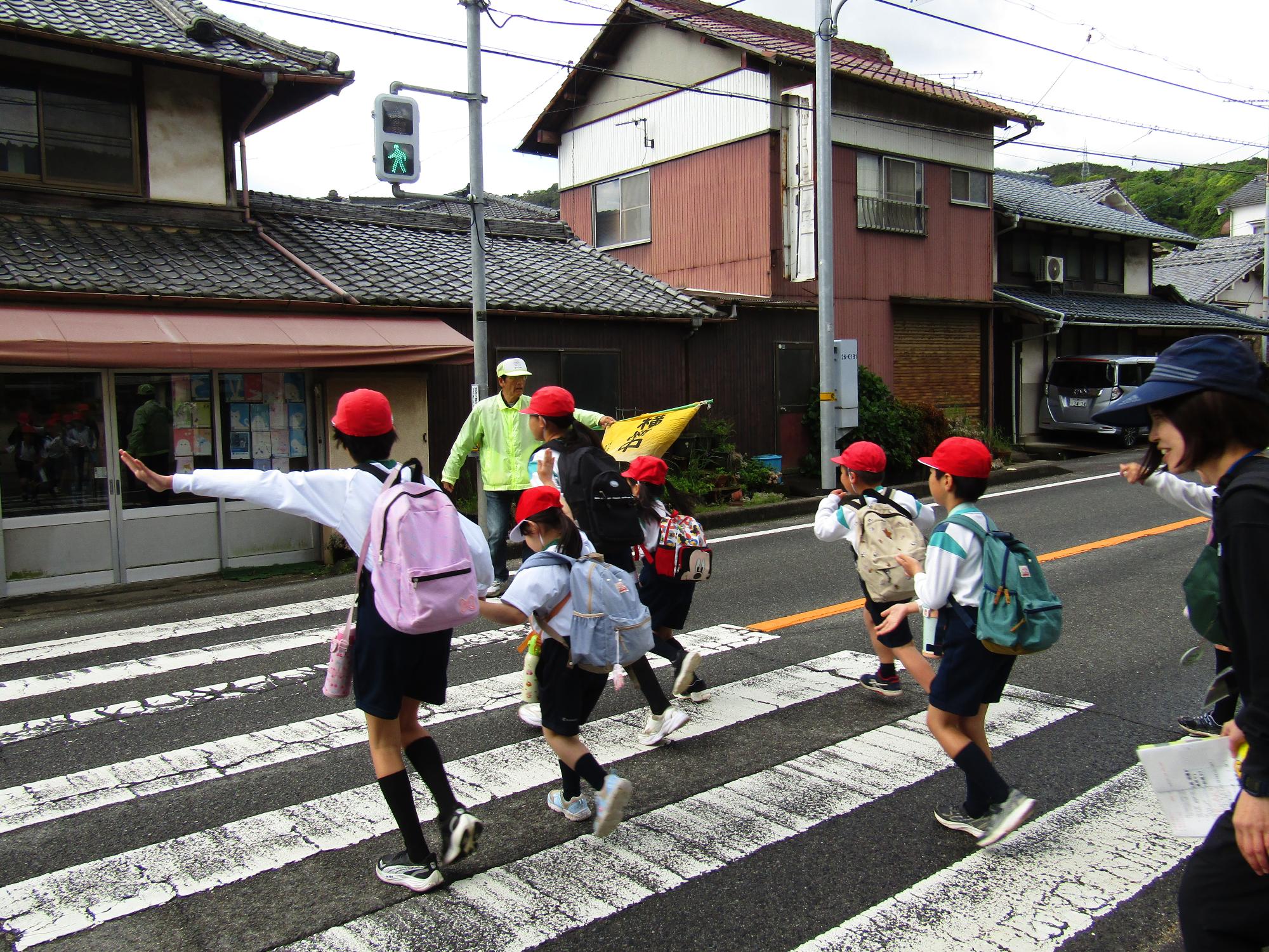 横断歩道を渡る児童と安全見守りのボランティアさん