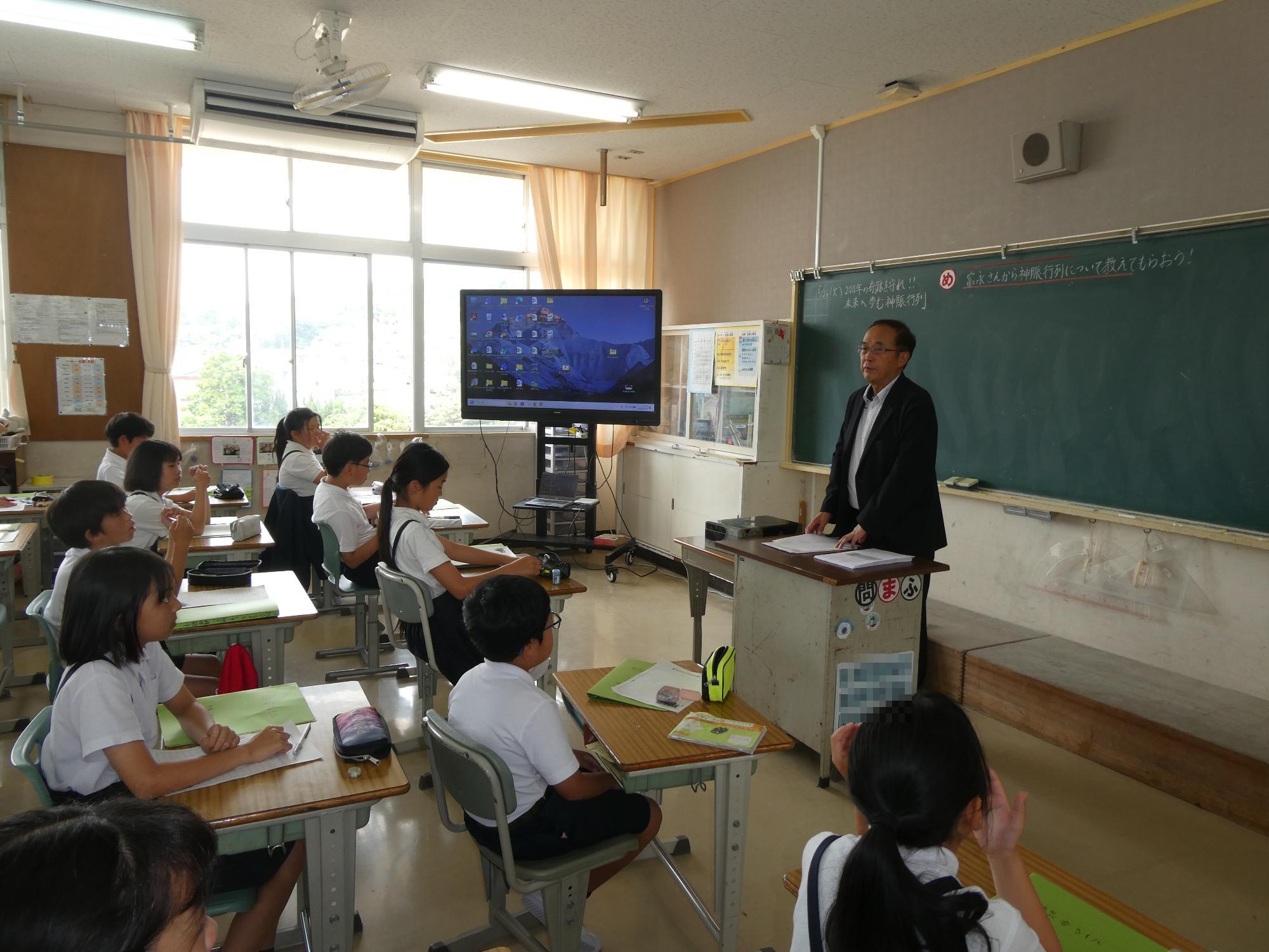教壇にたつ富永さんの話を聞く児童