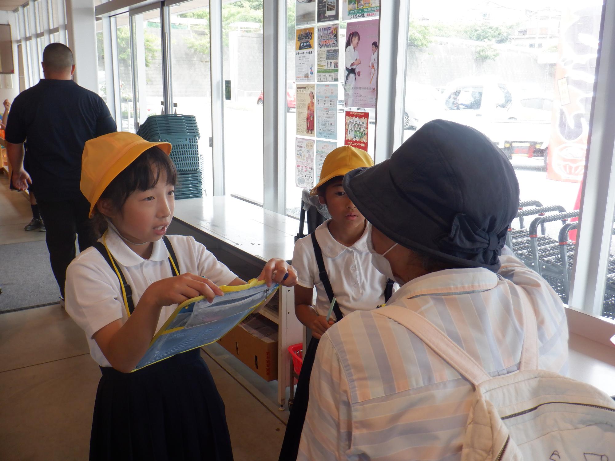 入口付近で買い物客に話を聞く女子児童