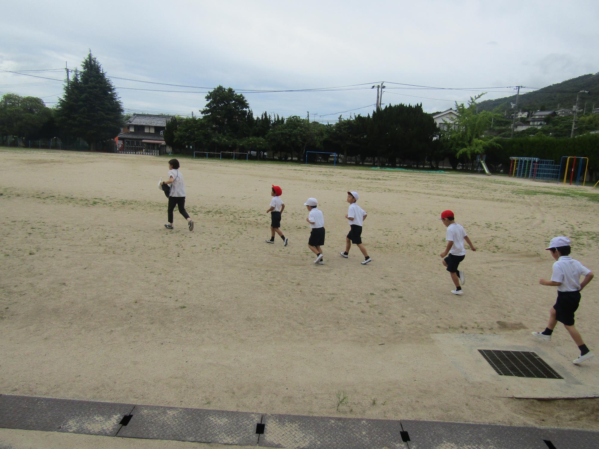 校庭を走る先生と児童
