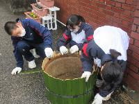 門松づくりで竹を枠にはめて土台を作っている生徒たち